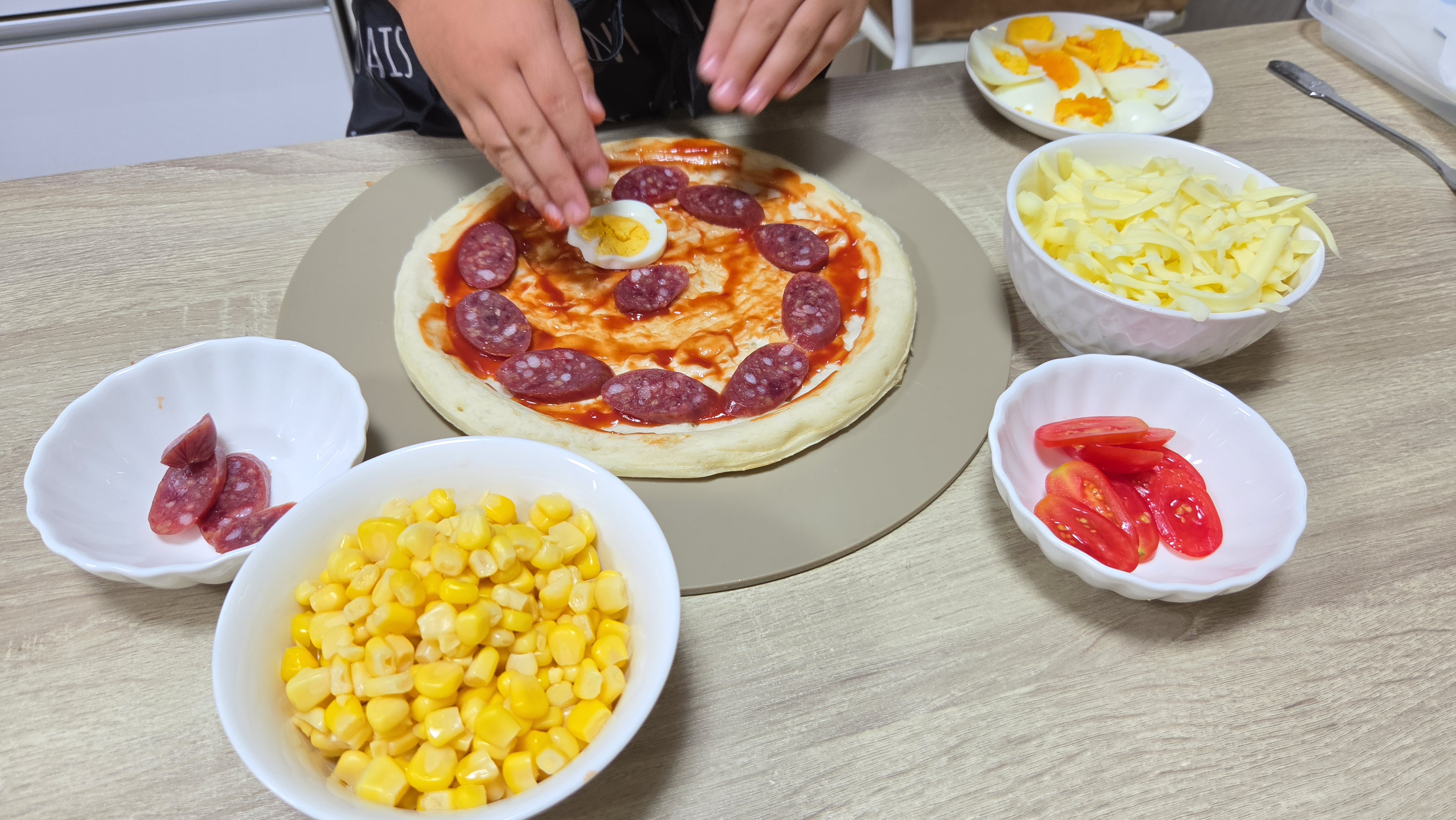 子どもの手でカルパスやミニトマトをトッピングしている様子